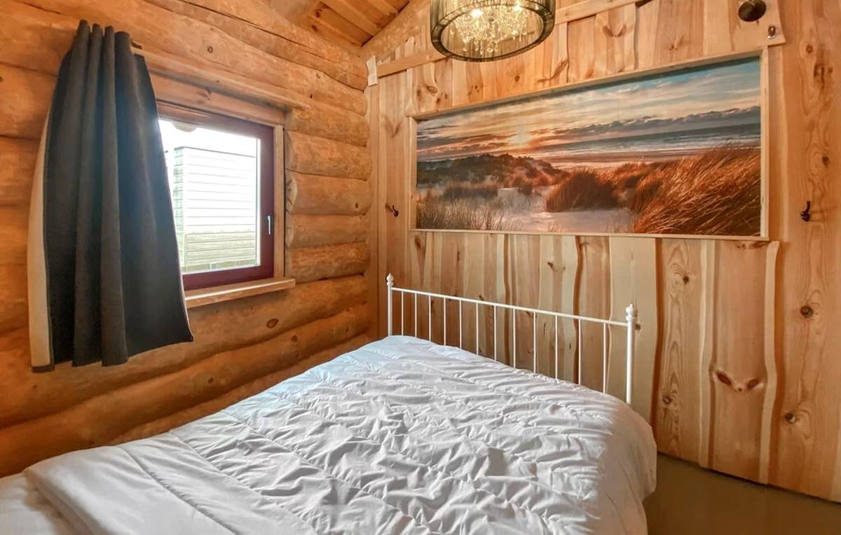 Slaapkamer met tweepersoonsbed onder een schilderij van de duinen